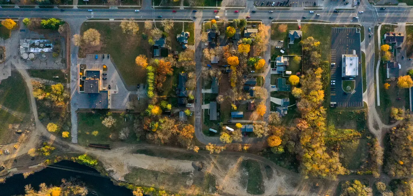 Drone view looking straight down on Plainwell in fall: the main road, businesses and parking lots, homes, and the Kalamazoo River