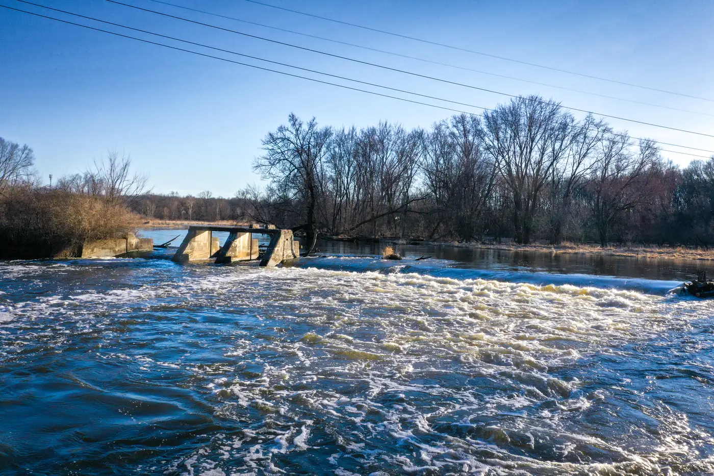 Rapids on the Kalamazoo River below an old dam, under a clear blue sky
