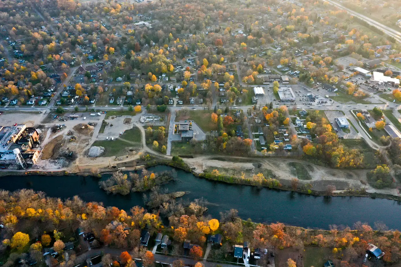 Drone view over Plainwell neighborhoods in fall color, with the Kalamazoo River in front