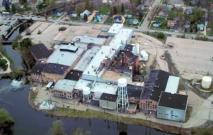 Aerial view of the paper mill buildings and water tower beside the Kalamazoo River