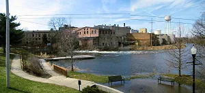 Former paper mill buildings and the water tower seen across the river from the riverwalk