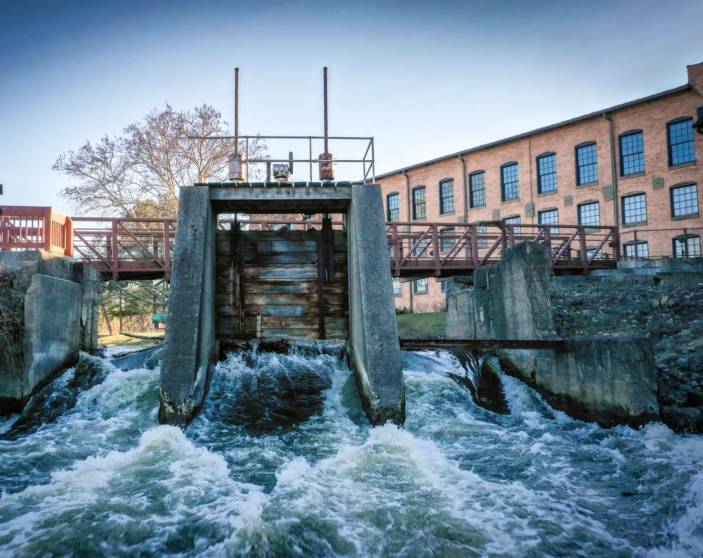 The spillway on the Kalamazoo River, with the footbridge and the brick mill buildings behind it